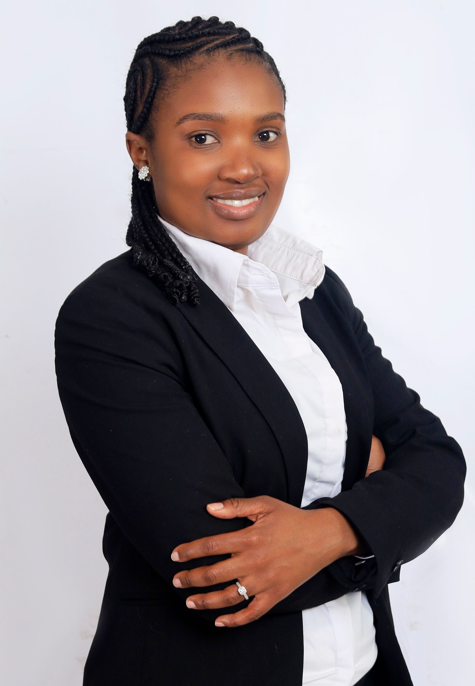 A business owner in a black suit stands with her arms folded and smiles to the camera.